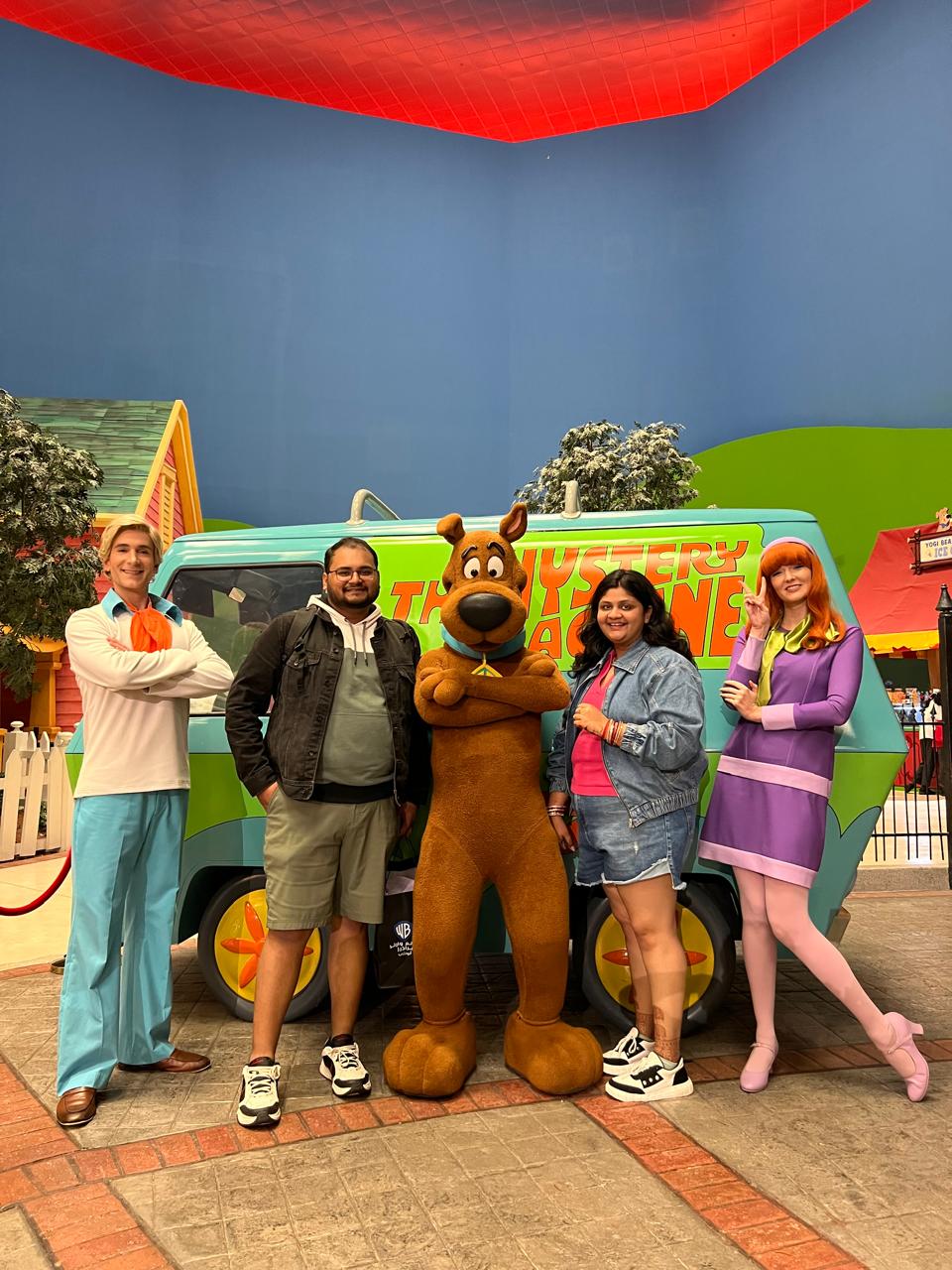 Salil and Eesha posing with cartoon characters at a theme park